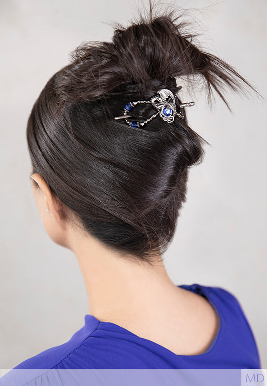 woman with hair styled up in a dragon flexi clip with blue stones that match her blue top