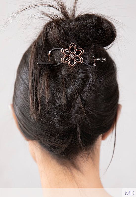 cute messy up hairstyle held by a black flexi clip with a copper flower centerpiece. 