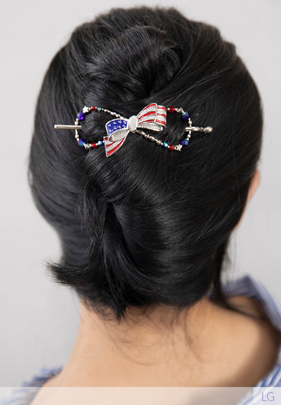 Betsy Flexi Clip shown in hair and features a patriotic bow bursting with bright blue and ruby red colors complemented by star bead accents.