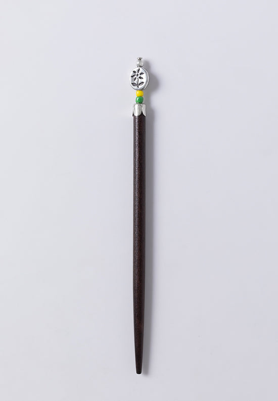 Sylvia hair stick features an oval button embossed with a flower, with green and yellow bead accents.