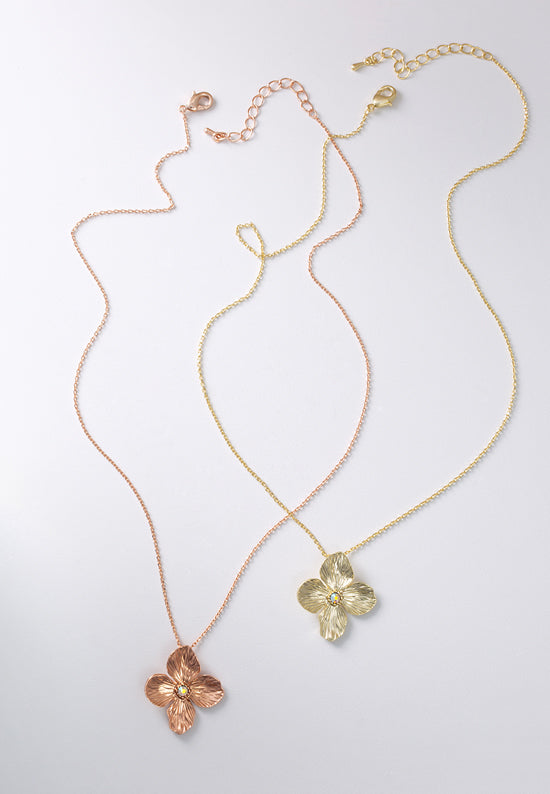 Posie necklaces in brasstone and rose goldtone feature a pure and precious flower with crystal aurora borealis center stone.