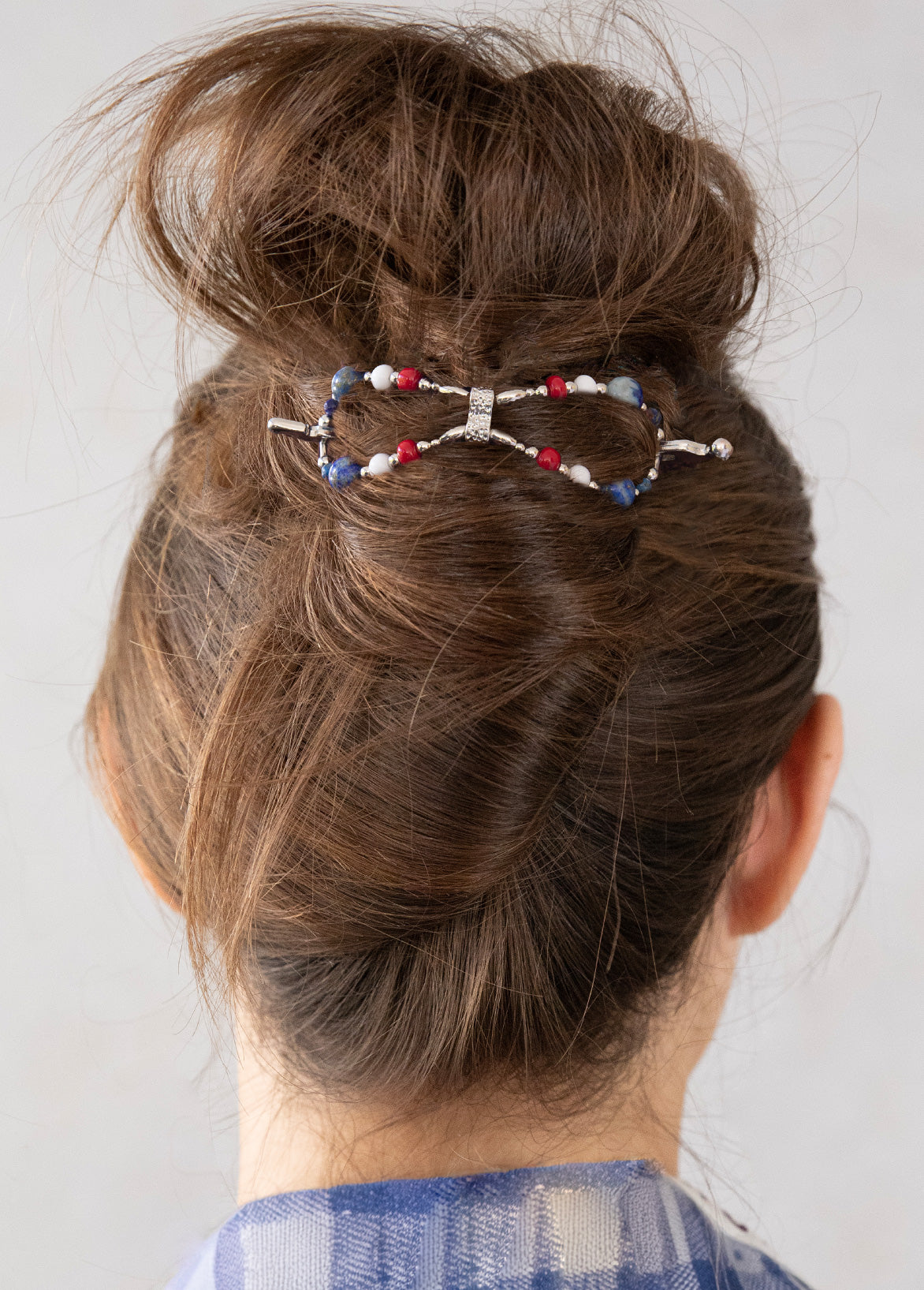 Hair bun with decorative hair clip on a plain background