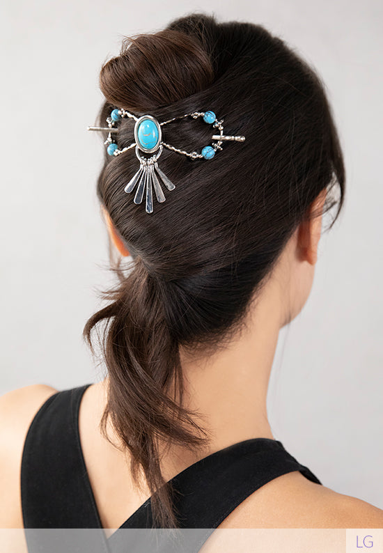 Tabitha Flexi Clip features an oval stoneset with paddle drops and natural howlite stone accents. Shown in hair in turquoise.
