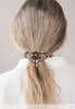 Nicoma Flexi Clip shown in hair and features a groovy flower round set in burnished coppertone with turquoise, cream and wood accents. 