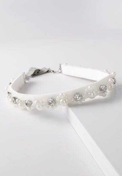 White hairband decorated with large pearls and crystals.