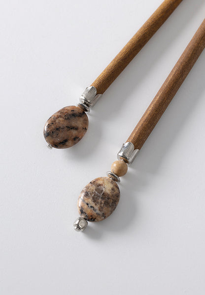 Annona hair stick features an oval feldspar natural stone with grainy accents and is available in two lengths.