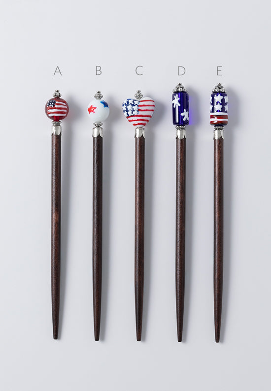 Patriotic hair sticks in a variety of five colorful designs including stars and stripes of red, white and blue.